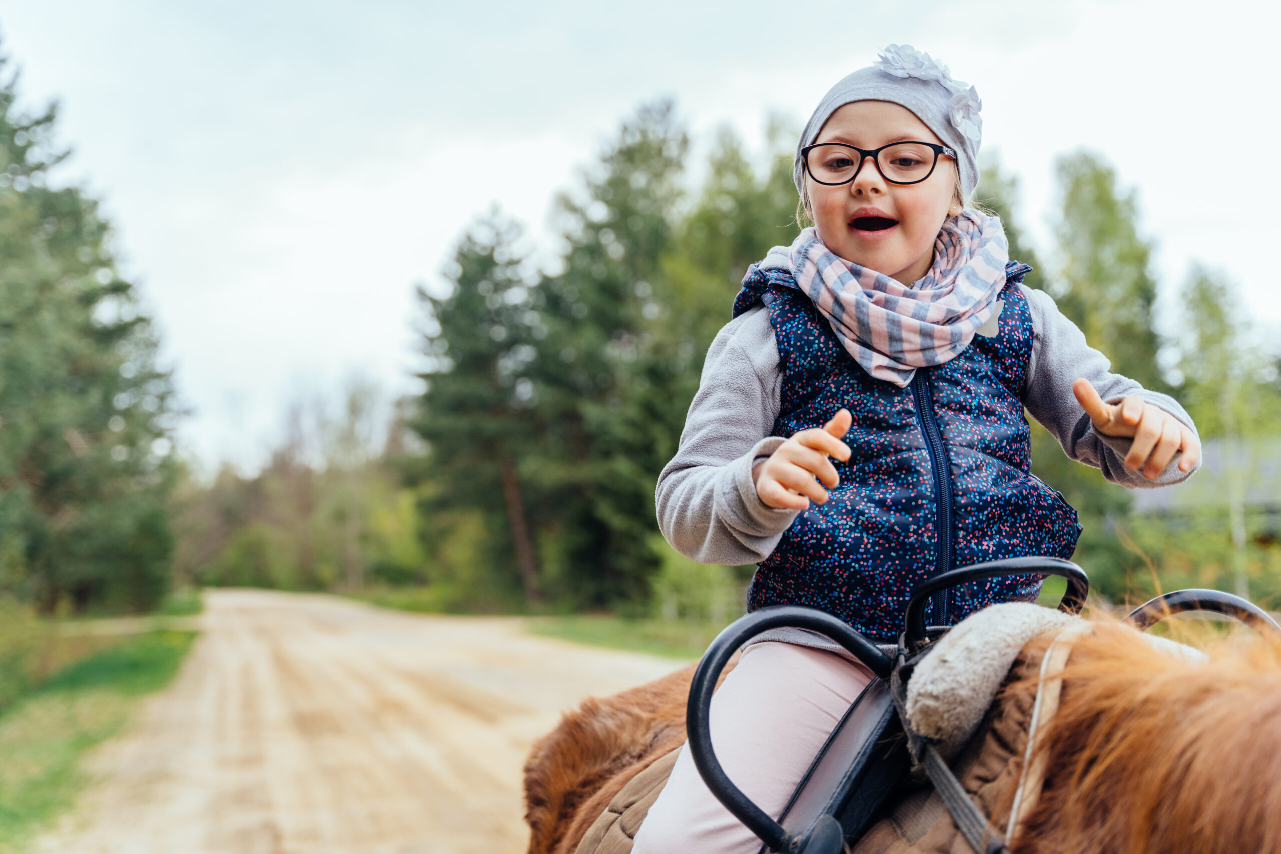 Little girl riding on a horseback. The girl is sitting on a horse . A child on a day walk on the ranch.